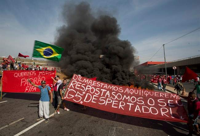 Members of the Homeless Workers Movement protest against the money spent on the World Cup near Itaquerao stadium which will host the international soccer tournament's first match in Sao Paulo, Brazil, Thursday, May 15, 2014. Brazilians are angry at the billions spent to host the World Cup, much of it on 12 ornate football stadiums, one-third of which critics say will see little use after the big event. The banner is a message for Brazil's President Dilma Rousseff. which reads in Portuguese: "Dilma, we're here. We want your answer. We're your wake up call." (AP Photo/Andre Penner)