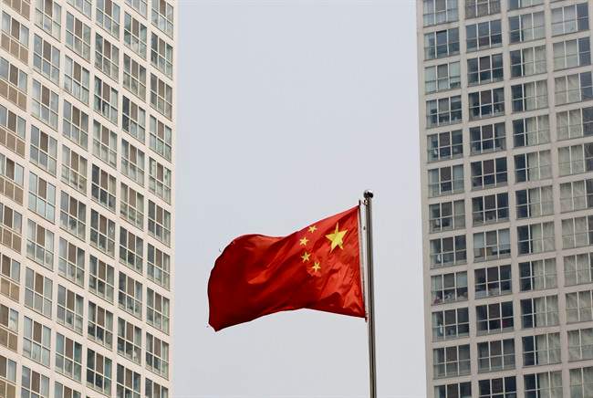 A Chinese national flag flutters in the wind in between a highrise residential and office complex in Beijing, China on Monday, May 19, 2014.