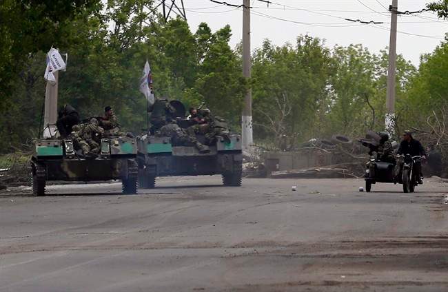 Pro-Russian gunmen atop armoured personal carriers passing by barricades on a road leading into Slovyansk, eastern Ukraine, Monday, May 5, 2014. 