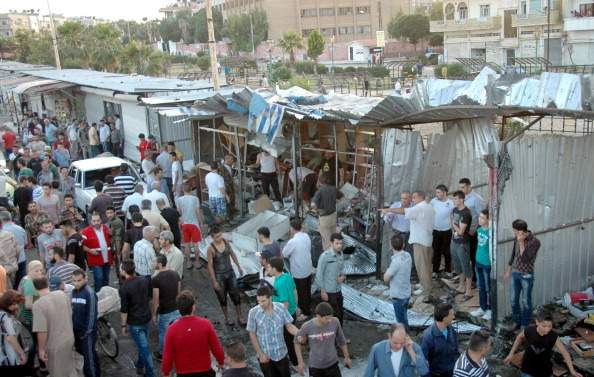 Syrian security forces and civilians inspect the site of a car bomb attack in Homs' Akrameh district, a majority Alawite neighbourhood, on June 19, 2014. 