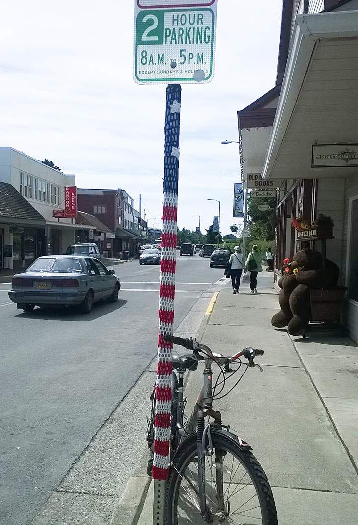 In this June 12, 2014 photo provided by Fran Hartman, the pole of a street sign is adorned with a pair of yarn flowers in Sitka, Alaska.
