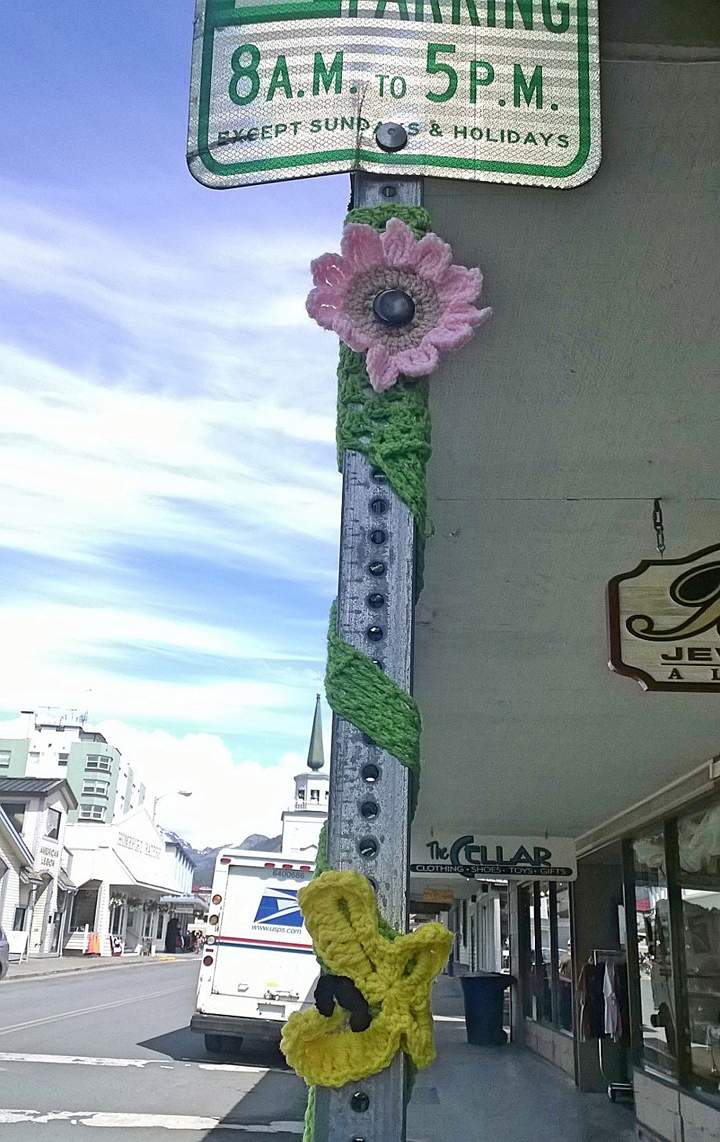 In this June 12, 2014 photo provided by Fran Hartman, the pole of a street sign is adorned with a pair of yarn flowers in Sitka, Alaska.