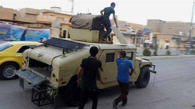 Teenagers ride on an armoured vehicle belonging to the Iraqi army in Tikrit, 130 kilometres north of Baghdad, Iraq, Wednesday, June 11, 2014. 