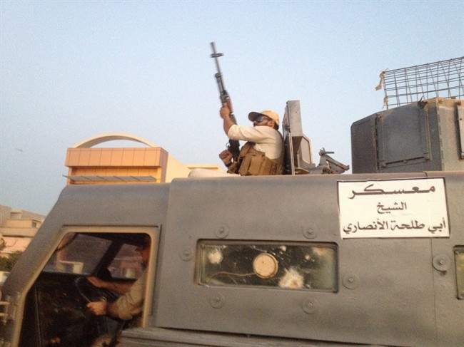 In this photo taken Monday, June 23, 2014, fighters of the al-Qaida-inspired Islamic State of Iraq and the Levant (ISIL) parade in a commandeered Iraqi security forces armoured vehicles down a main road at the northern city of Mosul, Iraq, more than two weeks after ISIL took over the country's second largest city.
