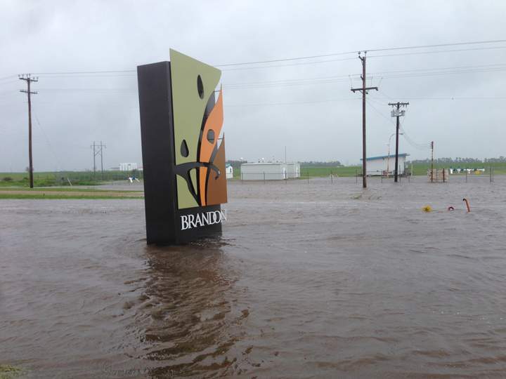 The sign welcoming visitors to Brandon, Man., is surrounded by a lake on Sunday. 