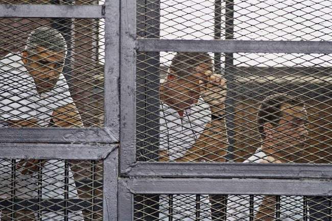FILE – In this Thursday, May 15, 2014 file photo, from left, Mohammed Fahmy, Canadian-Egyptian acting bureau chief of Al-Jazeera, Australian correspondent Peter Greste, and Egyptian producer Baher Mohamed appear in a defendant\’s cage along with several other defendants during their trial on terror charges at a courtroom in Cairo. Egypt’s state news agency says the trial of three Al-Jazeera English journalists and 17 others has adjourned until next week when the judge will deliver the verdict, five months after the trial opened. Fahmy, Greste and Baher have been in detention since December 29.