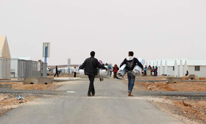 Men carry tarps through Azraq camp