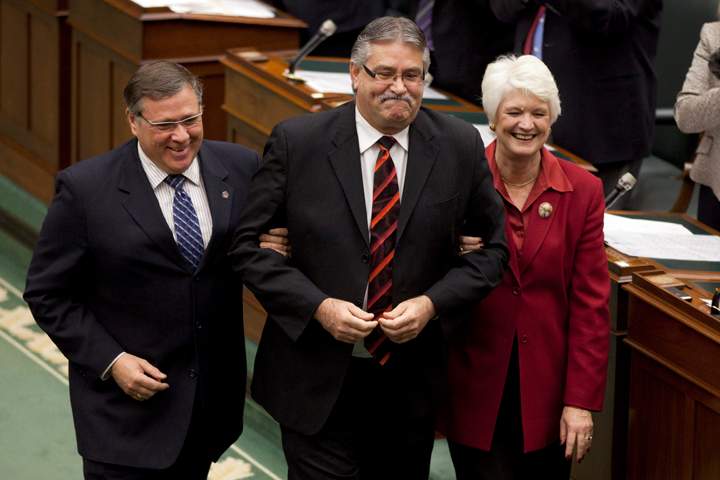 Newly elected Speaker of the Ontario Legislature, Liberal MPP Dave Levac (C) is guided towards the Speaker's chair by fellow MPP's Jerry Ouellette and Liz Sandals at Queen's Park Nov. 21 2011.