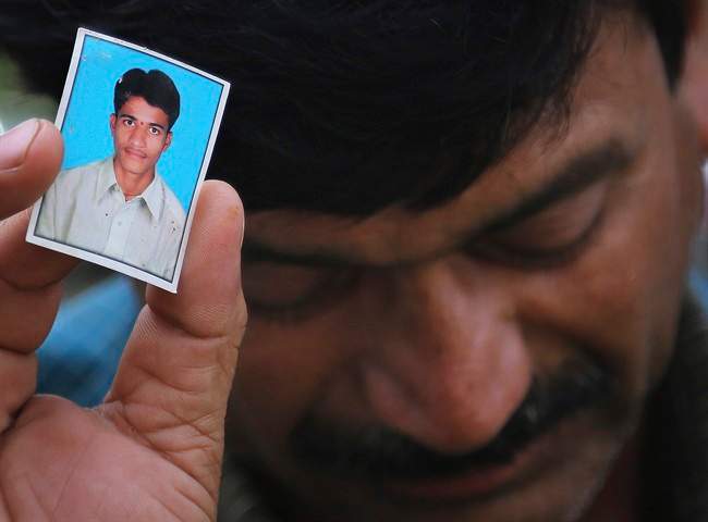 Bonath Shekar Naik shows a portrait of his son Rambabu, only one name available, one of the 24 students feared dead during a field trip near the mountain resort town of Manali, India, Monday, June 9, 2014. 
