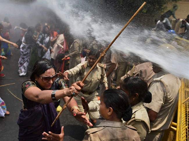 An Indian woman, left, one among the protestors demonstrating outside the office of Uttar Pradesh state chief minister Akhilesh Yadav, demanding that he crack down on an increasing number of rape and other attacks on women and girls, scuffles with police in Lucknow, India, Monday, June 2, 2014. 
