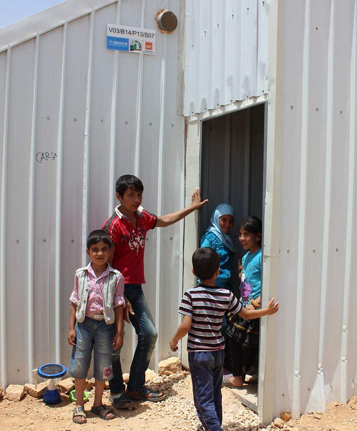 A family stands outside their shelter