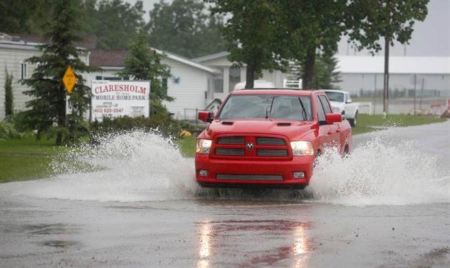 A truck sprays water as it’s driven through flood waters in Claresholm, Alta., Wednesday, June 18, 2014.