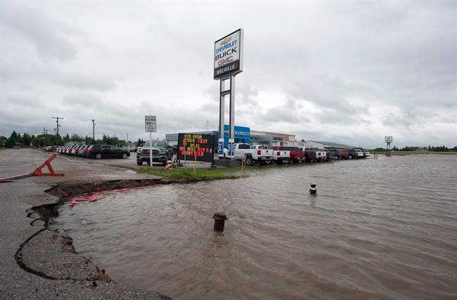 The ditches overflow with rain water near a car dealership in Melville, Saskatchewan on Sunday, June 29, 2014 . Highways are closing and communities are declaring states of emergency after a deluge of rain drenched southeast Saskatchewan and parts of Manitoba.