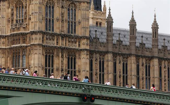 People stand on the Westminster Bridge, over the river Thames, backdropped by the Houses of Parliament in central London, Thursday, June 19, 2014.