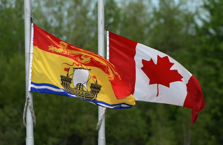 The New Brunswick and Canadian flags fly at half mast outside the Moncton Coliseum in Moncton, N.B. on Monday, June 9, 2014., where a regimental funeral will take place Tuesday for the the three RCMP officers who were slain in Moncton last week.