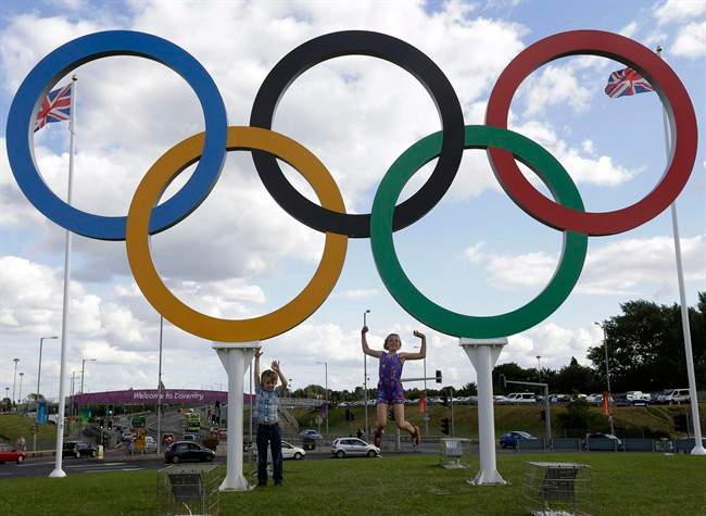 FILE - In this July 28, 2012 file photo, British children pose for photos under a sculpture of the Olympics rings, in Coventry, England. Boston, Los Angeles, San Francisco and Washington are the cities still in the running for a possible U.S. bid to host the 2024 Summer Olympics.
