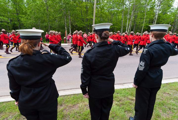 Royal Canadian Sea Cadets salute as RCMP officers march in the funeral procession on their way to the regimental funeral for three slain RCMP officers in Moncton, N.B., Tuesday, June 10, 2014.