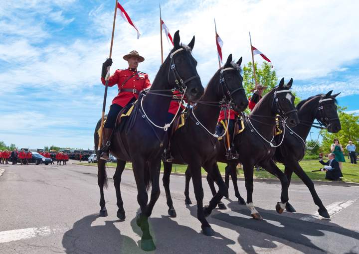 RCMP officers on horseback take part in the funeral procession on their way to the regimental funeral for three slain RCMP officers in Moncton, N.B., Tuesday, June 10, 2014.