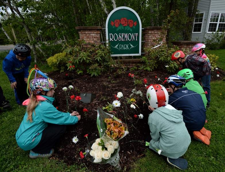 Youngster place flowers in a entrance garden to the neighbourhood of Rosemont Park in Moncton, N.B. on Saturday, June 7, 2014. THE CANADIAN PRESS/Sean Kilpatrick