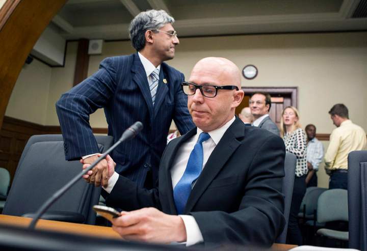 Don Guy, right, shakes hands with chair Shafiq Qaadri as he checks messages on his phone after attending the Justice Committee hearing in Toronto on Tuesday, August 13, 2013.