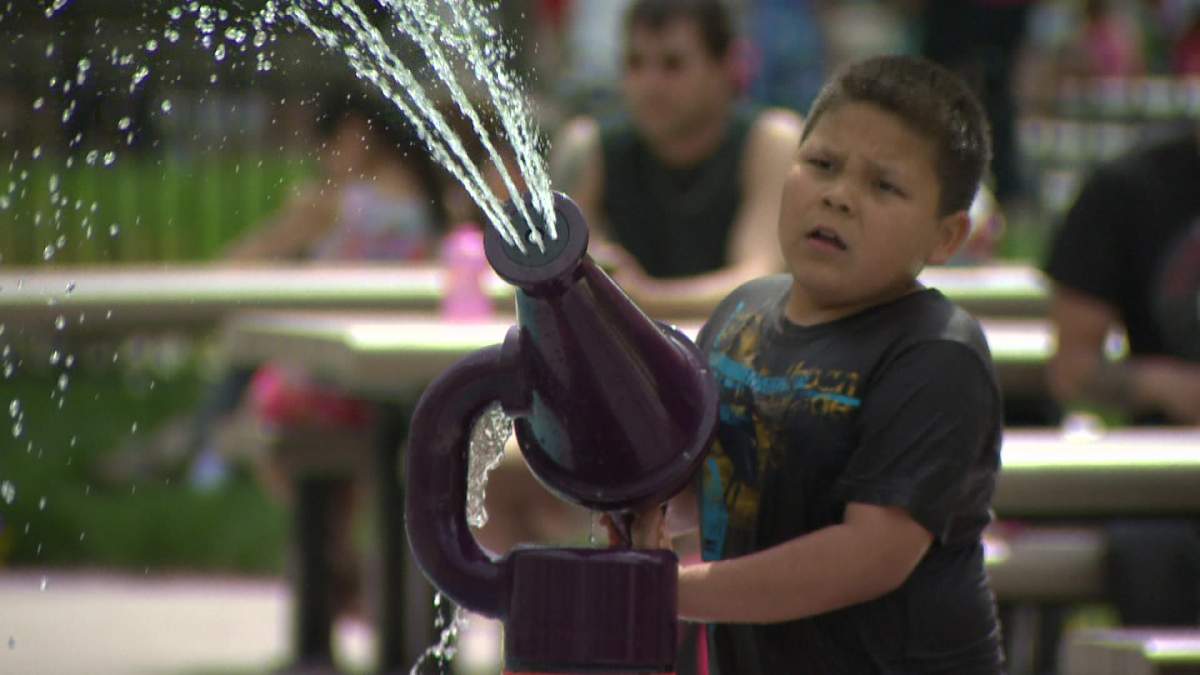 A boy plays at a spray pad.