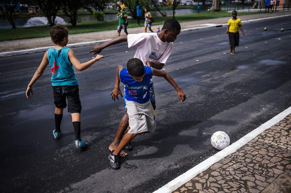 Brazilian children play football on a street near the Fonte Nova Arena stadium in Salvador on June 8, 2014, ahead of the 2014 FIFA World Cup in Brazil. AFP PHOTO / DIMITAR DILKOFF (Photo credit should read DIMITAR DILKOFF/AFP/Getty Images)