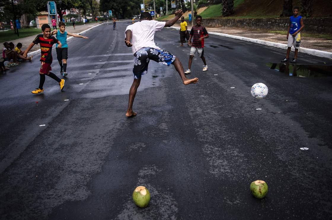 Brazilian children play football on a street near the Fonte Nova Arena stadium in Salvador on June 8, 2014, ahead of the 2014 FIFA World Cup in Brazil. AFP PHOTO / DIMITAR DILKOFF (Photo credit should read DIMITAR DILKOFF/AFP/Getty Images)