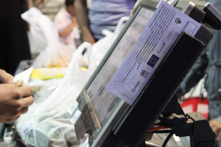 A customer pays for their groceries using a voucher
