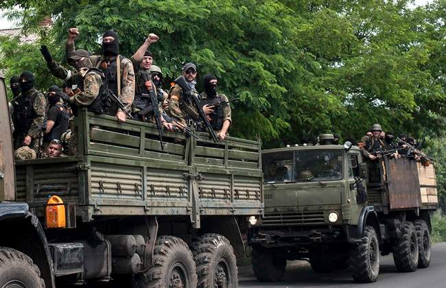 Ukrainian troops stand atop vehicles as they leave a site of a battle in Mariupol, eastern Ukraine, Friday, June 13, 2014. 