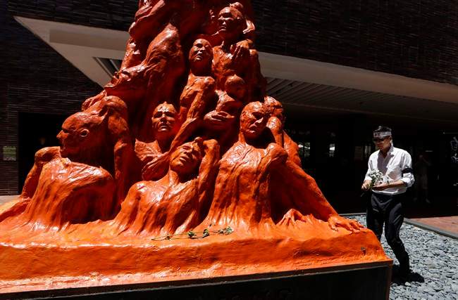 A man places flowers on the “Pillar of Shame” statue, which commemorates the June 4, 1989 military crackdown on a pro-democracy student movement, in the University of Hong Kong Wednesday, June 4, 2014.