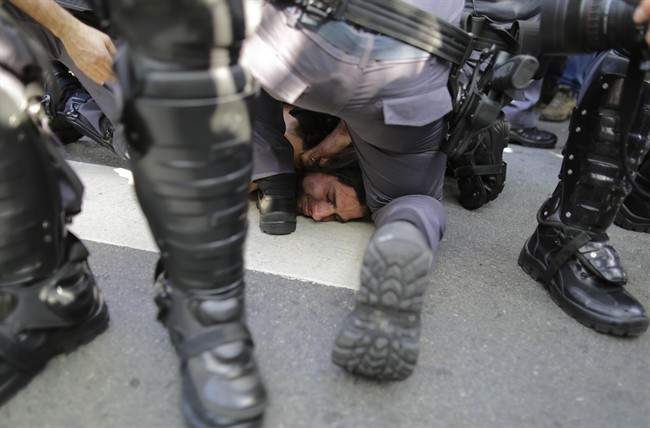 A protester is detained by police during a demonstration demanding better public services and protesting the money spent on the World Cup soccer tournament in Sao Paulo, Brazil, Thursday, June 12, 2014.