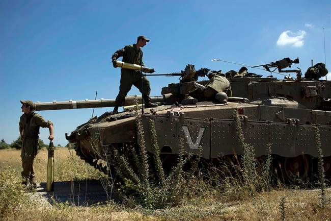 Israeli soldiers load shells in their tank following the first death on the Israeli side of the Golan since the Syrian civil war erupted more than three years ago, near the Israeli village of Alonei Habashan, in the area of Tel Hazeka, close to the Quneitra border crossing in the Israeli-controlled Golan Heights, Sunday, June 22, 2014. 