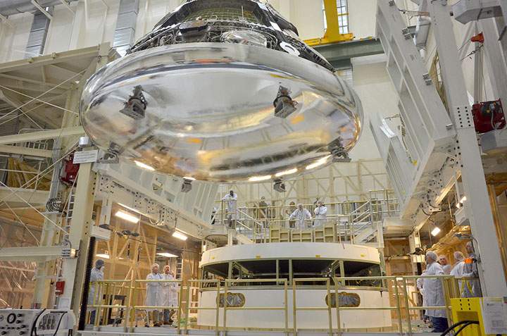 The Orion crew module – the next step in human space exploration – is positioned over the service module just prior to mating the two sections together.