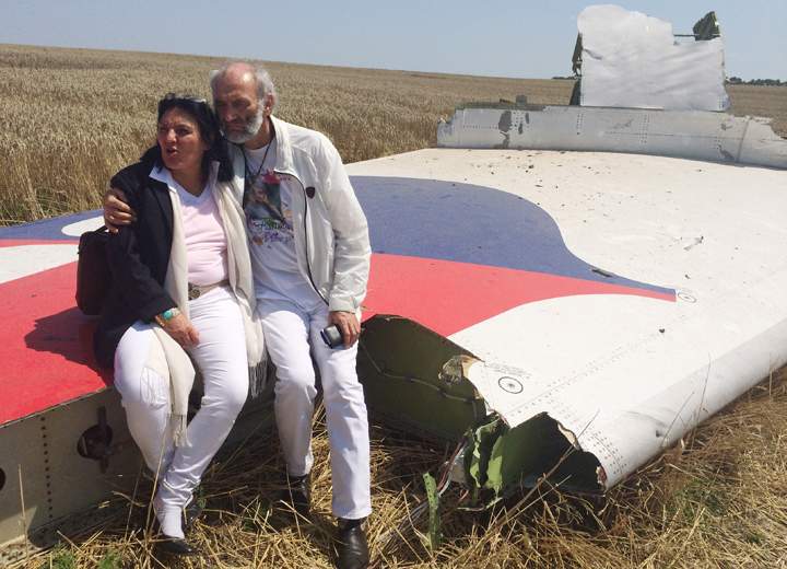 Jerzy Dyczynski and Angela Rudhart-Dyczynski whose daughter, 25-year-old Fatima, was a passenger on Malaysia Airlines flight MH17, sit on part of the wreckage of the crashed aircraft in Hrabove, Ukraine, Saturday, July 26, 2014.