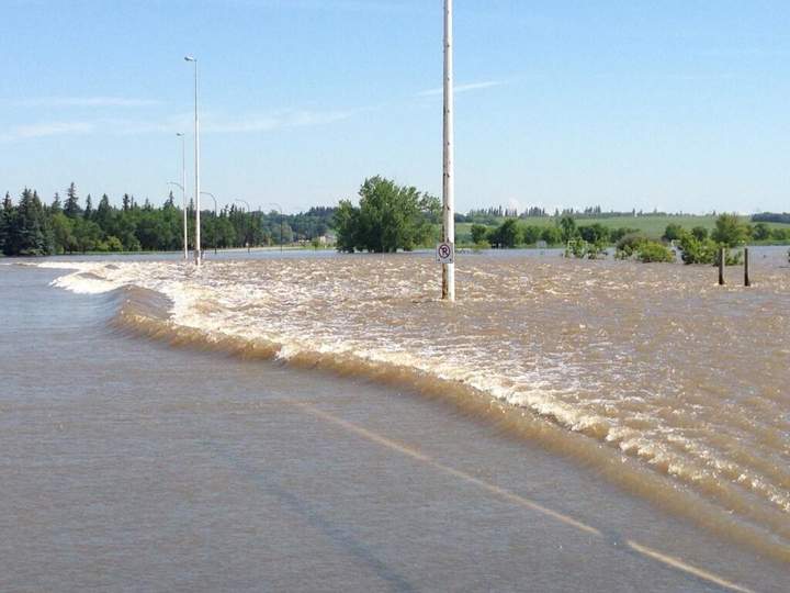 Water washes over First Street in Brandon, Man., on Saturday.