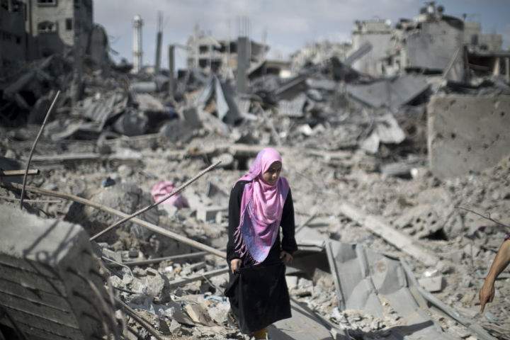 Palestinian woman walks across the rubble of destroyed buildings and homes in the Shejaiya residential district of Gaza City on July 26, 2014. 