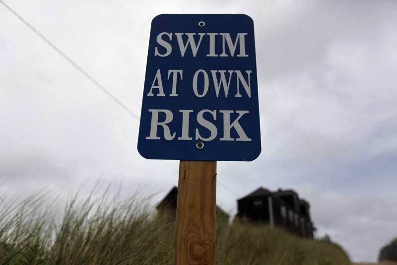 A sign reads 'Swim at Own Risk' at Ballston Beach on Cape Cod on August 12, 2012 in Truro, Massachusetts. (Photo by Mario Tama/Getty Images).