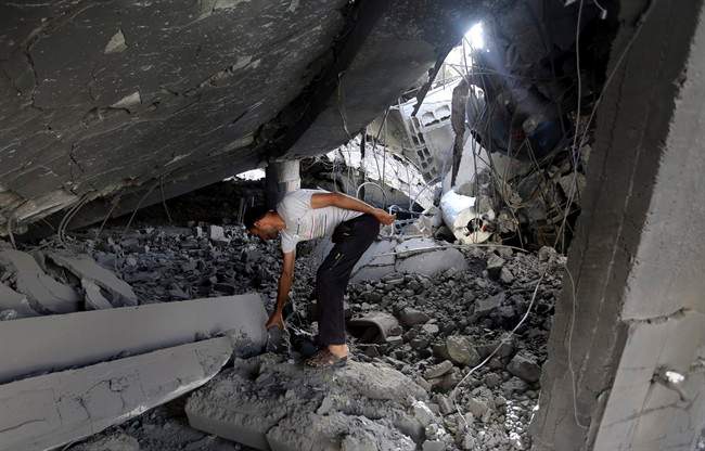 A Palestinian searches the ruins of the Al-Tawfeeq mosque after it was hit by an Israeli missile strike in the Nuseirat refugee camp, central Gaza Strip, Saturday, July 12, 2014.