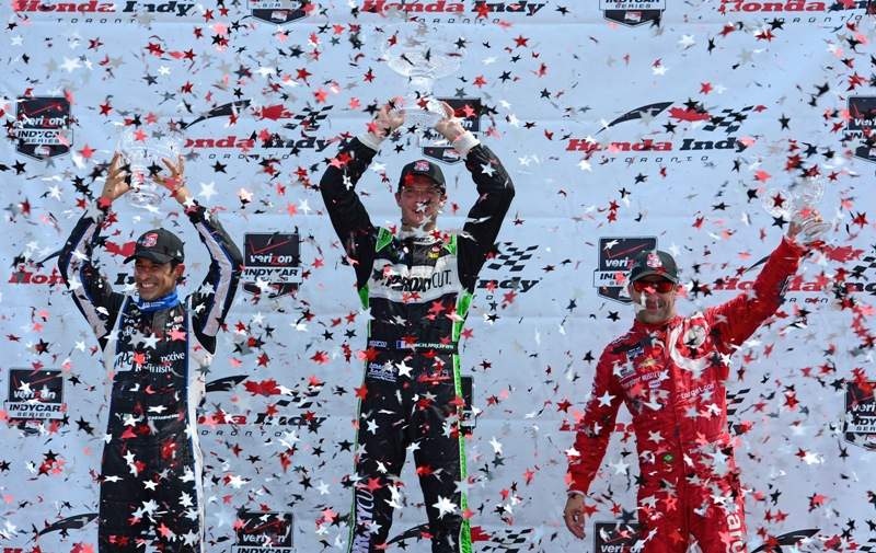 FILE- Helio Castroneves of Brazil , Sebastien Bourdais of France  and Tony Kanaan of Brazil celebrate their respective second, first and third places during race 1 of the Verizon IndyCar Series Honda Indy Toronto on the streets of Toronto on July 20, 2014, in Toronto, Canada.