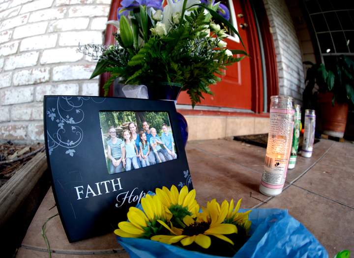 A photograph, flowers and candles are left on the porch where a fatal home shooting took place Thursday, July 10, 2014, in Spring, Texas.