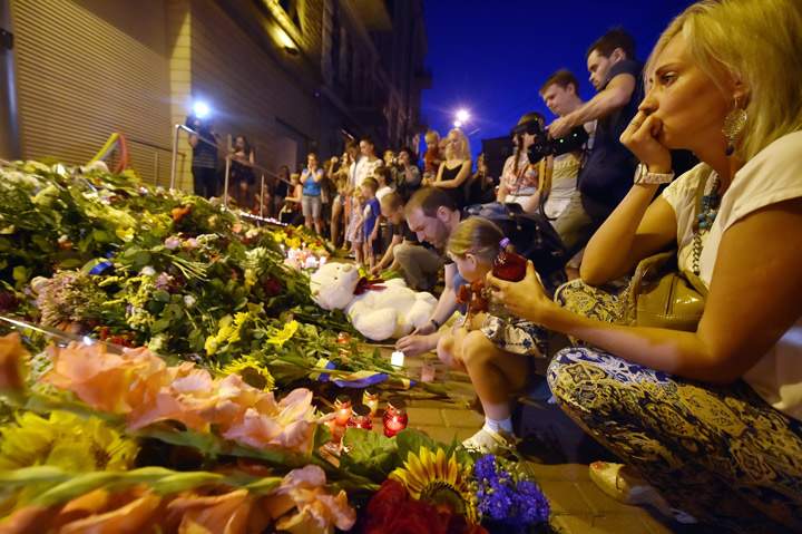 A woman looks on before lighting a candle in front of the Embassy of the Netherlands in Kiev.