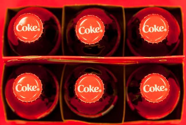 FILE - This July 15, 2013 file photo shows bottle tops of Coca-Cola 8 oz. bottles in Doral, Fla. The Coca-Cola Co. reports quarterly financial results before the market opens on Tuesday, July 22, 2014. (AP Photo/Wilfredo Lee, File)