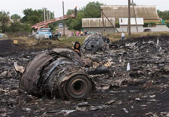 A woman walks at the site of a crashed Malaysia Airlines passenger plane near the village of Rozsypne, eastern Ukraine Friday, July 18, 2014. 