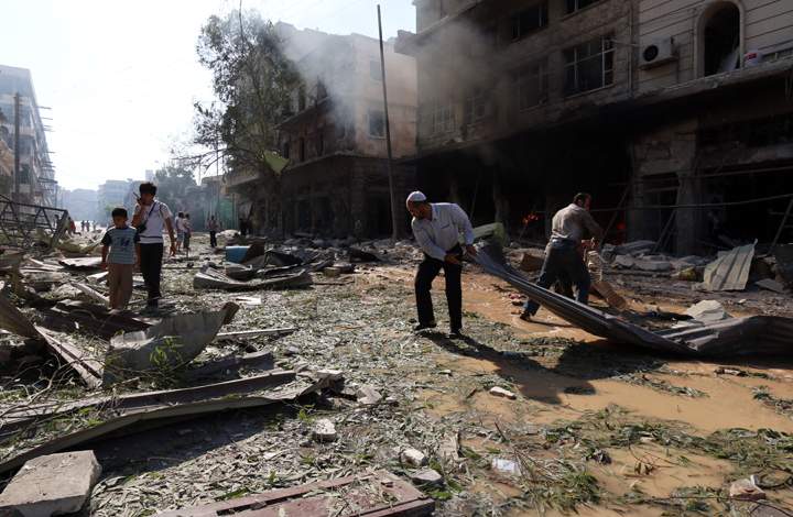 People inspect the damages at the site of a reported barrel-bomb attack by Syrian government forces in the northern city of Aleppo on July 20, 2014. 
