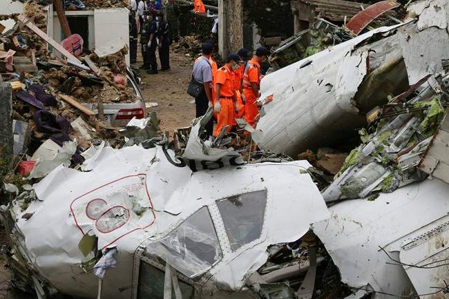 Rescue workers survey the wreckage of TransAsia Airways Flight GE222 on the Taiwanese island of Penghu Thursday, July 24, 2014. The plane attempting to land in stormy weather crashed on the island late Wednesday, killing more than 40 people and wrecking houses and cars on the ground.