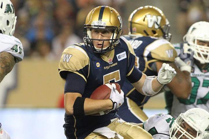 Quarterback Drew Willy #5 of the Winnipeg Blue Bombers is held by Trevor Guyton #92 of the Saskatchewan Roughriders at Investors Group Field on Thursday.