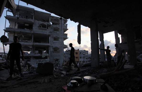 Palestinians collect their usable belongings among the debris of buildings destroyed in Israeli shelling  in Al Shaaf neighborhood of Gaza City, Gaza on August 18, 2014. (Photo by Ashraf Amra/Anadolu Agency/Getty Images).