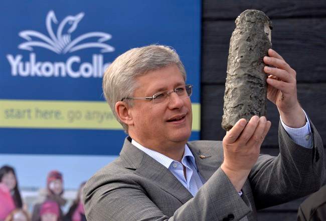 Prime Minister Stephen Harper holds up a permafrost core sample as he takes part in an event at the Yukon college in Whitehorse, Thursday August 21, 2014. 