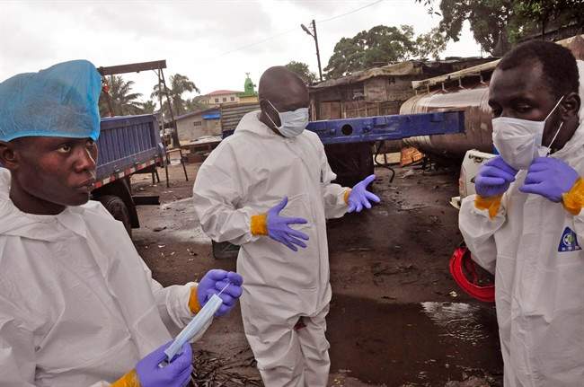 Liberian health worker prepare their Ebola protective gear before removing the body of a man that they believe died from the Ebola virus in Monrovia, Liberia, Friday, Aug. 29, 2014. 