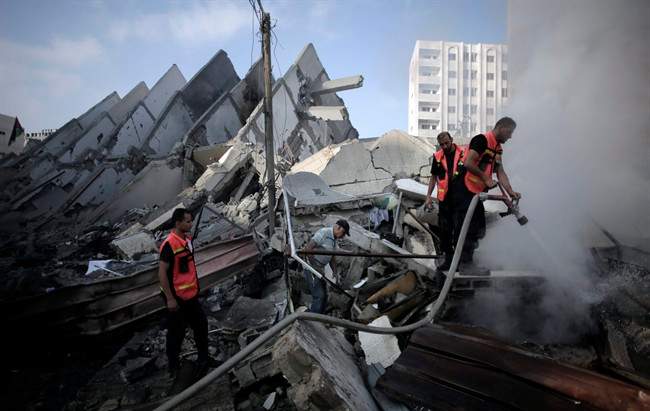In this Tuesday, Aug. 26, 2014 file photo, Palestinian firefighters extinguish a fire in the rubble of the destroyed 15-story Basha Tower, following early morning Israeli airstrikes in Gaza City. 